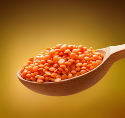 Red-orange lentil in a wooden spoon