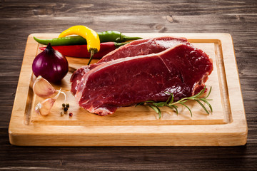 Raw beef on cutting board and vegetables