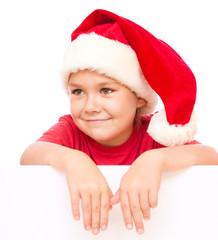 Little girl in santa hat is holding blank board