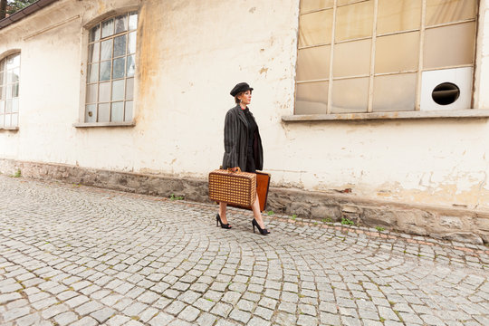 Woman walking on the street porphyry with suitcases