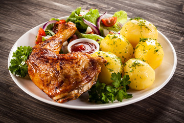 Barbecued chicken leg with boiled potatoes and vegetables