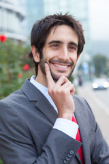 Lachender Geschäftsmann mit Bart vor Bürogebäude