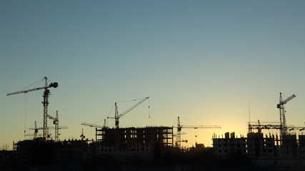 silhouettes of construction  and power lines at sunset