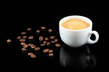 Coffee beans and fresh coffee in white cup on black background