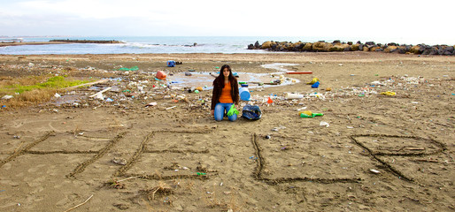 Sad ecologist asking for help sitting on beach full of dirt
