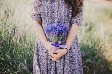 Woman in blue floral dress with cornflowers in hands