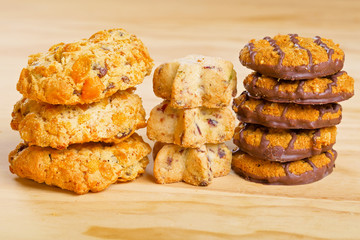 Different cookies in piles on wooden table