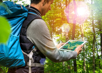 Fototapeta na wymiar Wanderer mit Tablet-PC beim Wandern Wald Gegenlicht