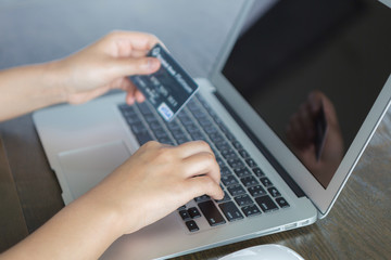 Hands holding a credit card and using laptop computer for online