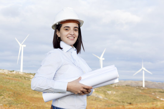 Female engineer holding blueprints at wind turbine site