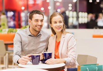 Fototapeta premium happy couple with shopping bags drinking coffee