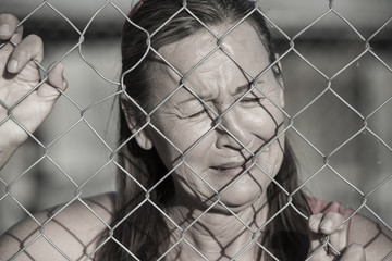 Stressed Crying woman at prison fence