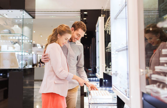 happy couple choosing engagement ring in mall