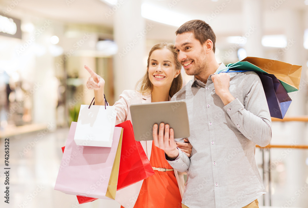 Poster couple with tablet pc and shopping bags in mall