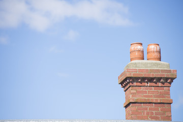 Red brick chimney on roof with blue sky