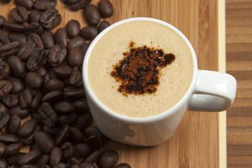 Cappuccino and spilled out coffee beans.