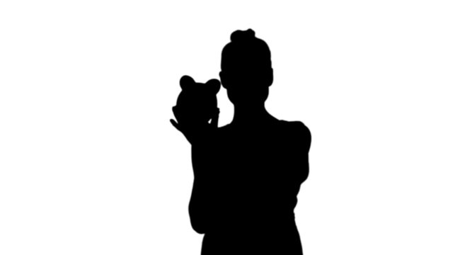 Woman shaking piggy bank in black silhouette