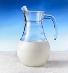Jug of milk on sky background. Half full pitcher