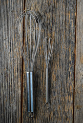 Large and Small Whisk on Rustic Wood Background