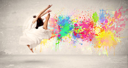 Naklejka na ściany i meble Happy teenager jumping with colorful ink splatter on urban backg