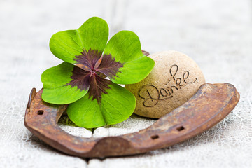 Glücksbringer und Stein auf Holz, Danke