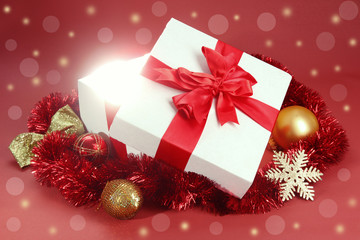 Gift box with bright light on it on red background