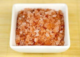 Bowl of pink himalyan rock salt against wooden background