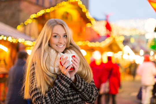 Junge Frau trinkt Gl&uuml;hwein auf dem Weihanchtsmarkt