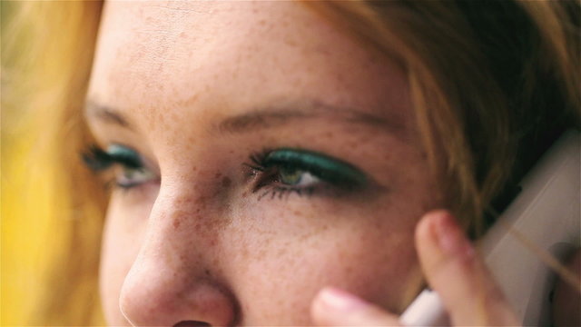 Woman with blue eyes and freckles talking on cellphone, closeup