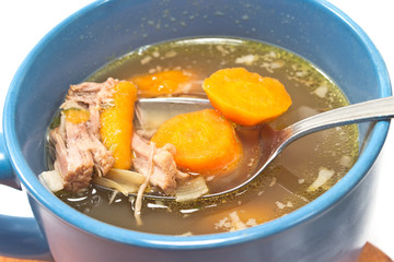 Beef and vegetable broth in  bowl with spoon