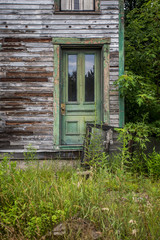 Fototapeta na wymiar Green exterior door on neglected abandoned house