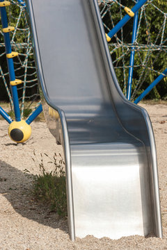 Metal slide with rope ladder and labyrinth in background.