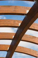 Timber frame arch against blue sky midday underneath view.