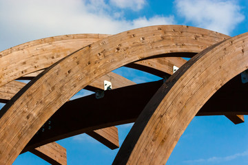 Timber frame arch against blue sky midday.