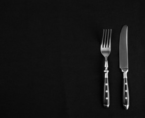 Fine cutlery on black placemat as menu board