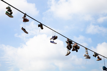 Old Shoes hanging on electrical wire against a blue sky