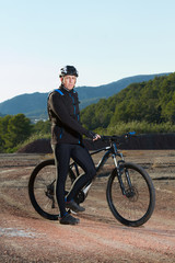 Obraz premium Cyclist standing with mountain bike in nature