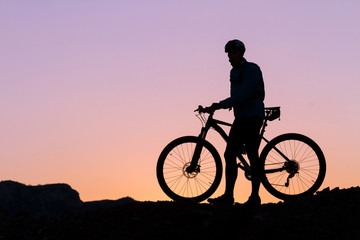 Silhouette of a cyclist with sunset on the top of a hill