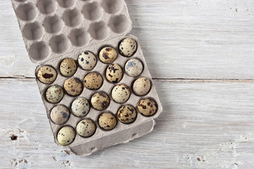 Quail eggs in the cardboard packing on the white table