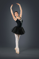 Beautiful female ballet dancer on a grey background.