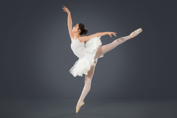 Beautiful female ballet dancer on a grey background.