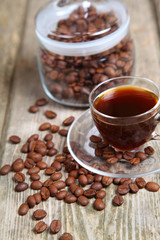 Transparent cup of coffee and coffee beans with the bank