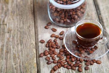 Transparent cup of coffee and coffee beans with the bank