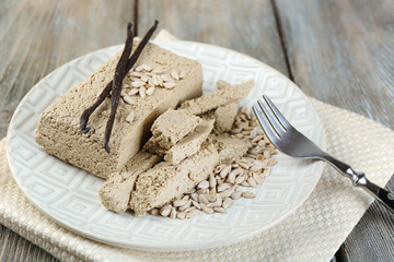 Sunflower halva on plate, on wooden background