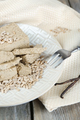 Sunflower halva on plate, on wooden background