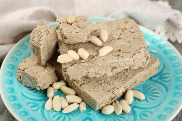 Sunflower halva with peanuts on plate, on wooden background