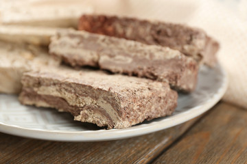 Two kinds of sunflower halva on plate, on wooden background