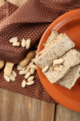 Sunflower halva with peanuts on plate, on wooden background