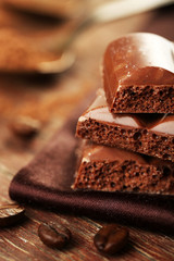 Tasty porous chocolate with cocoa beans, on wooden table