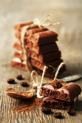 Tasty porous chocolate with coffee beans, on wooden table